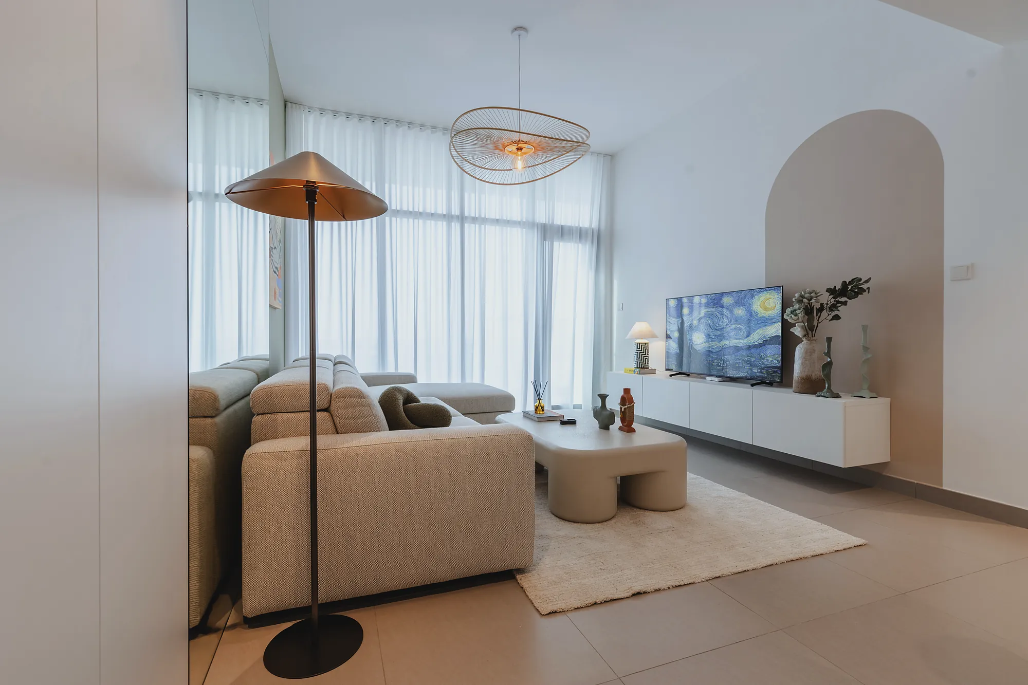 Prive 702 living area with sheer curtains, rattan pendant and sculptural coffee table