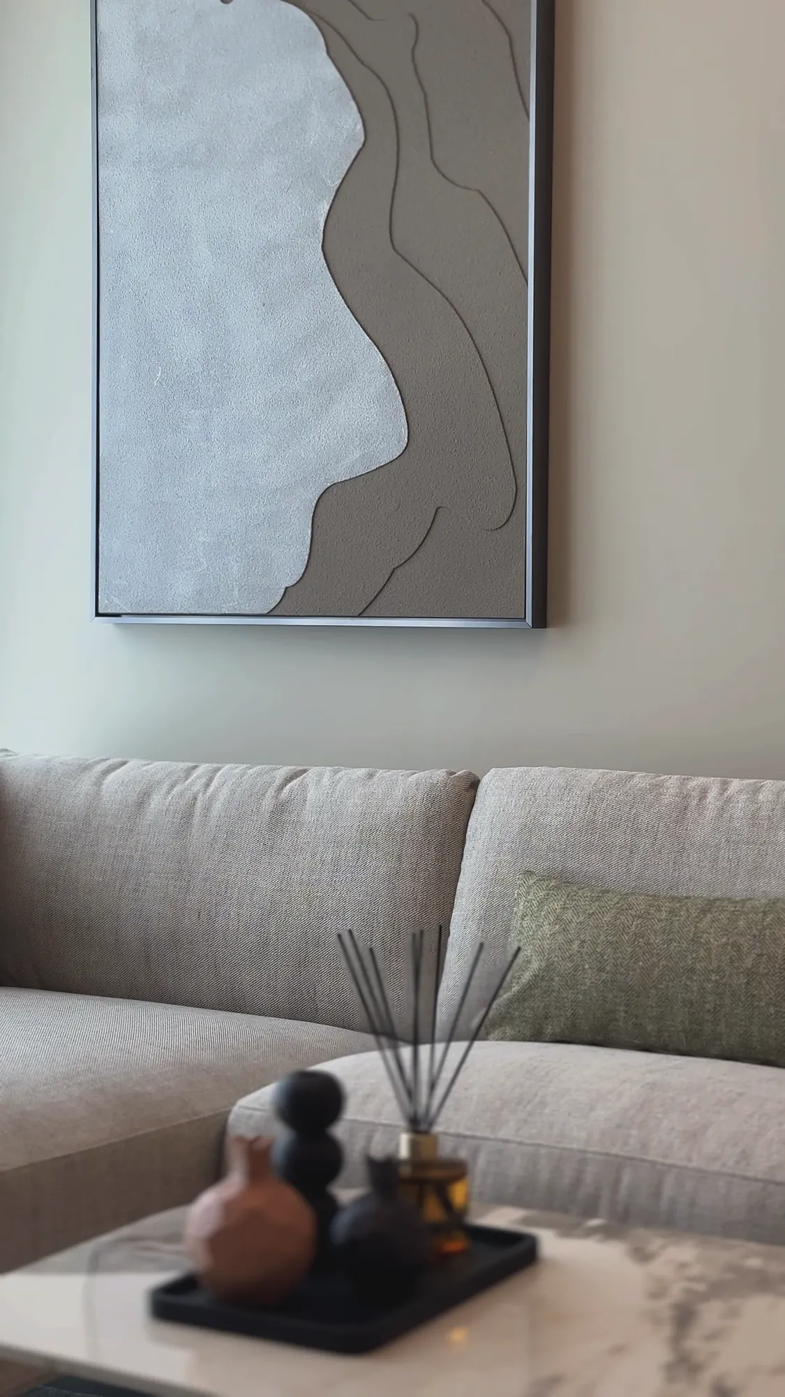 Burj Crown lounge corner with textured wall art above a linen sofa, residential fit-out in Dubai