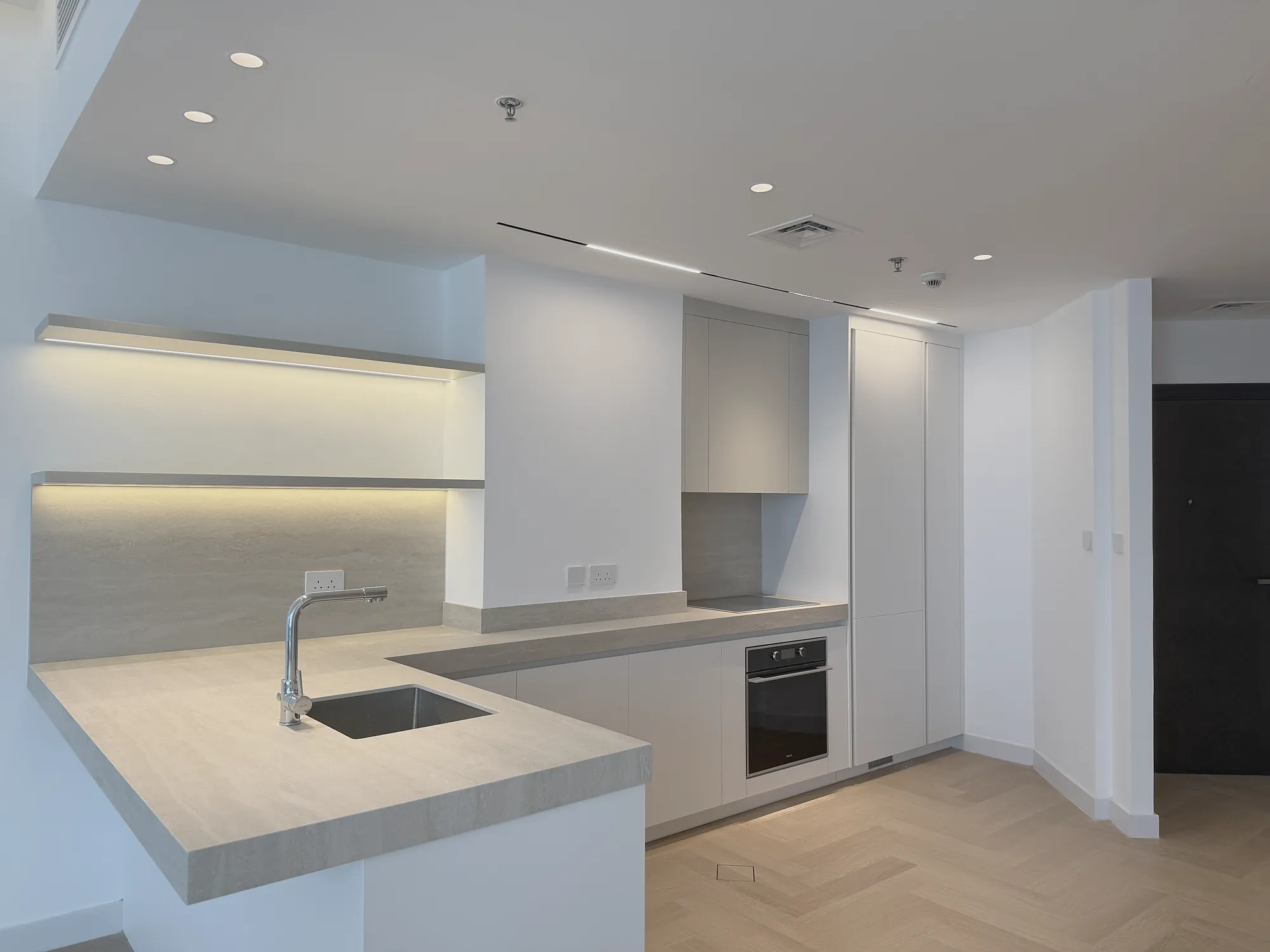 Marina Apartment kitchen with stone worktops, lit open shelving and handleless joinery, residential fit-out in Dubai