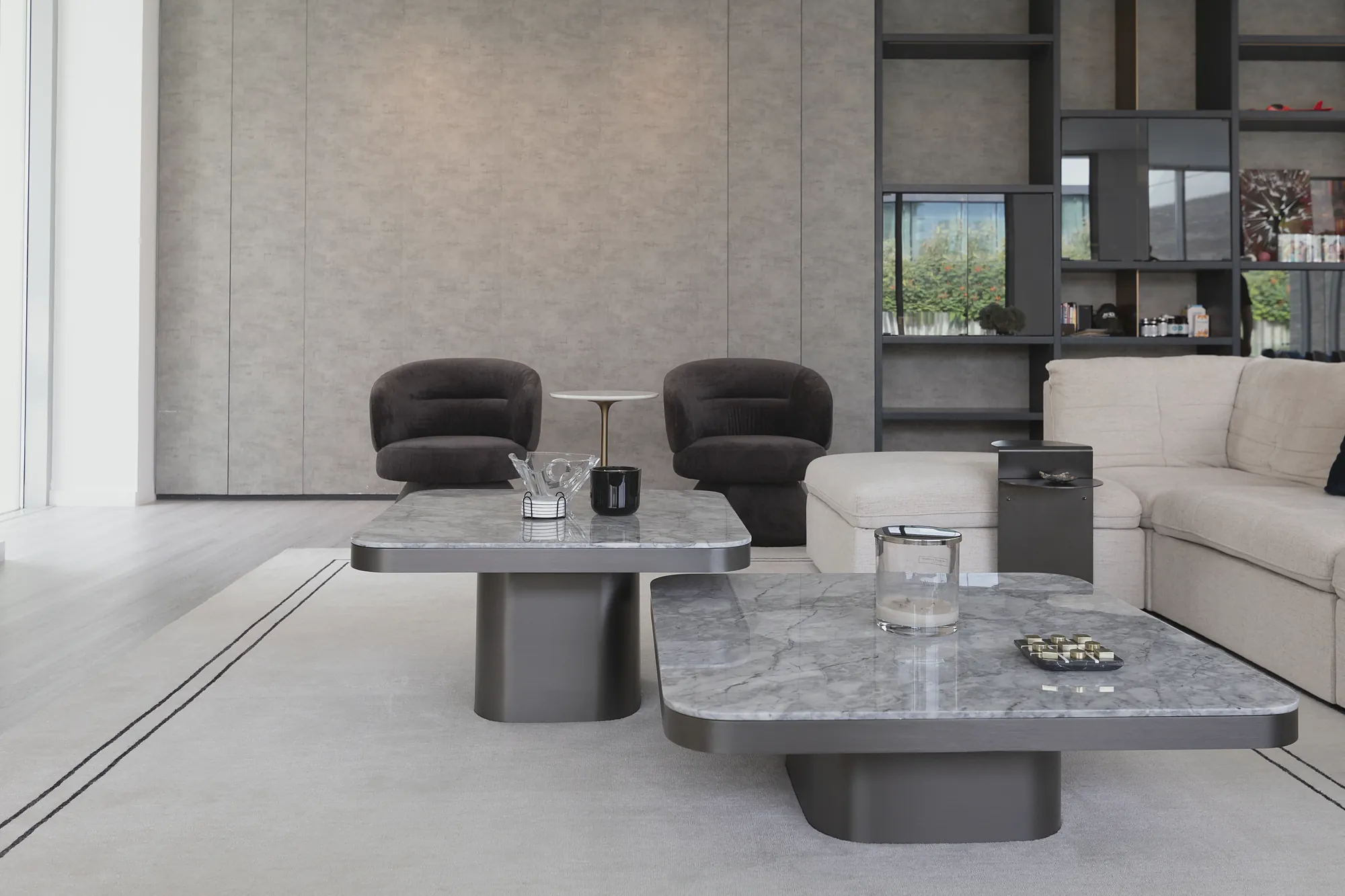 Parkway Vistas living room with grey marble coffee tables, dark lounge chairs and shelving wall