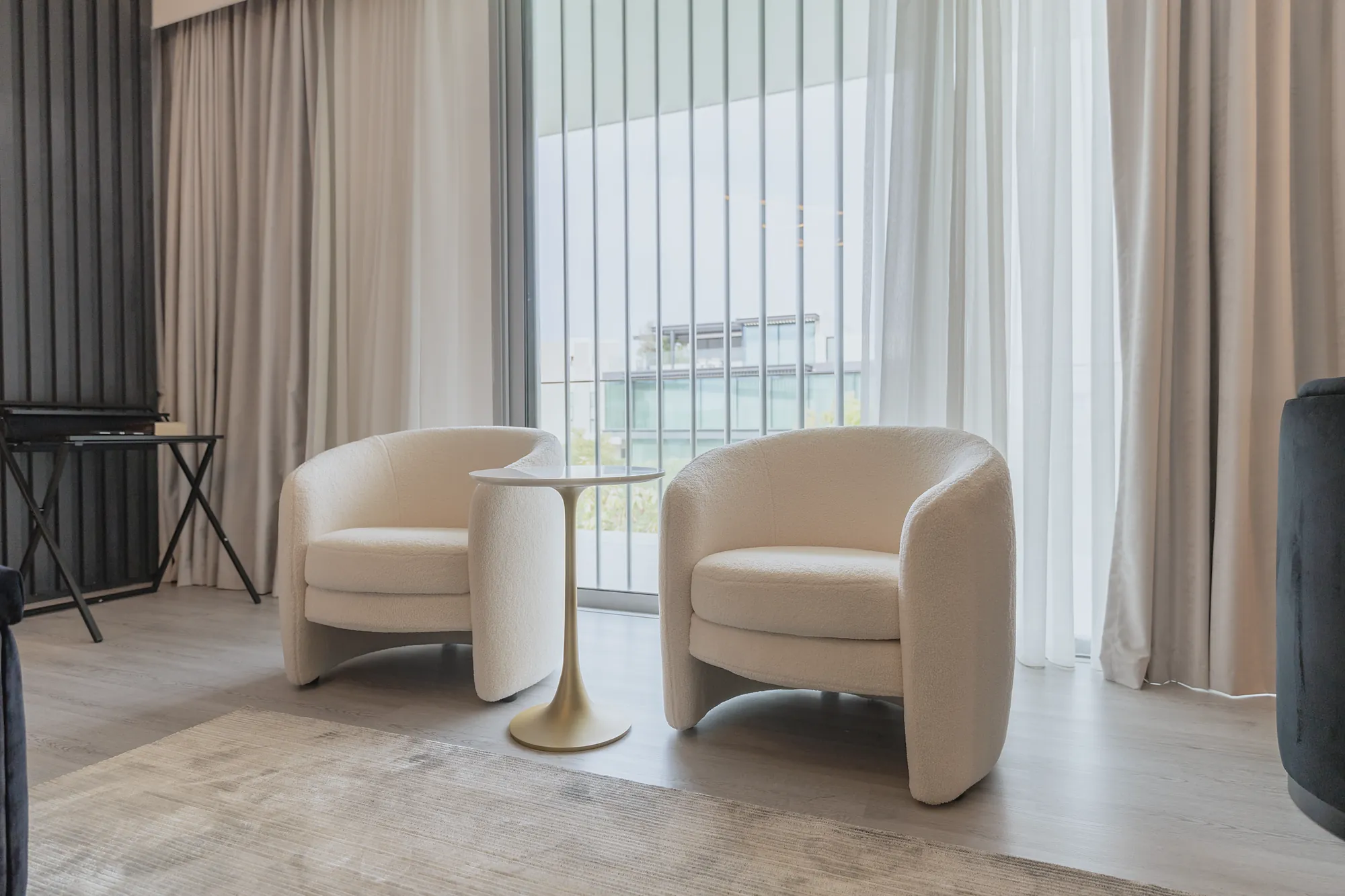 Parkway Vistas lounge corner with boucle armchairs, brass side table and full-height curtains