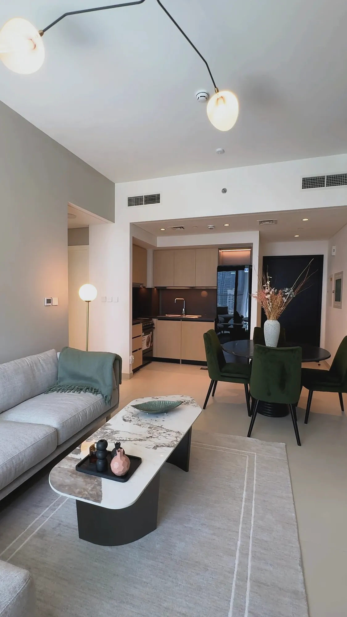 Burj Crown open living and dining area with green velvet chairs and oak kitchen, residential fit-out in Dubai