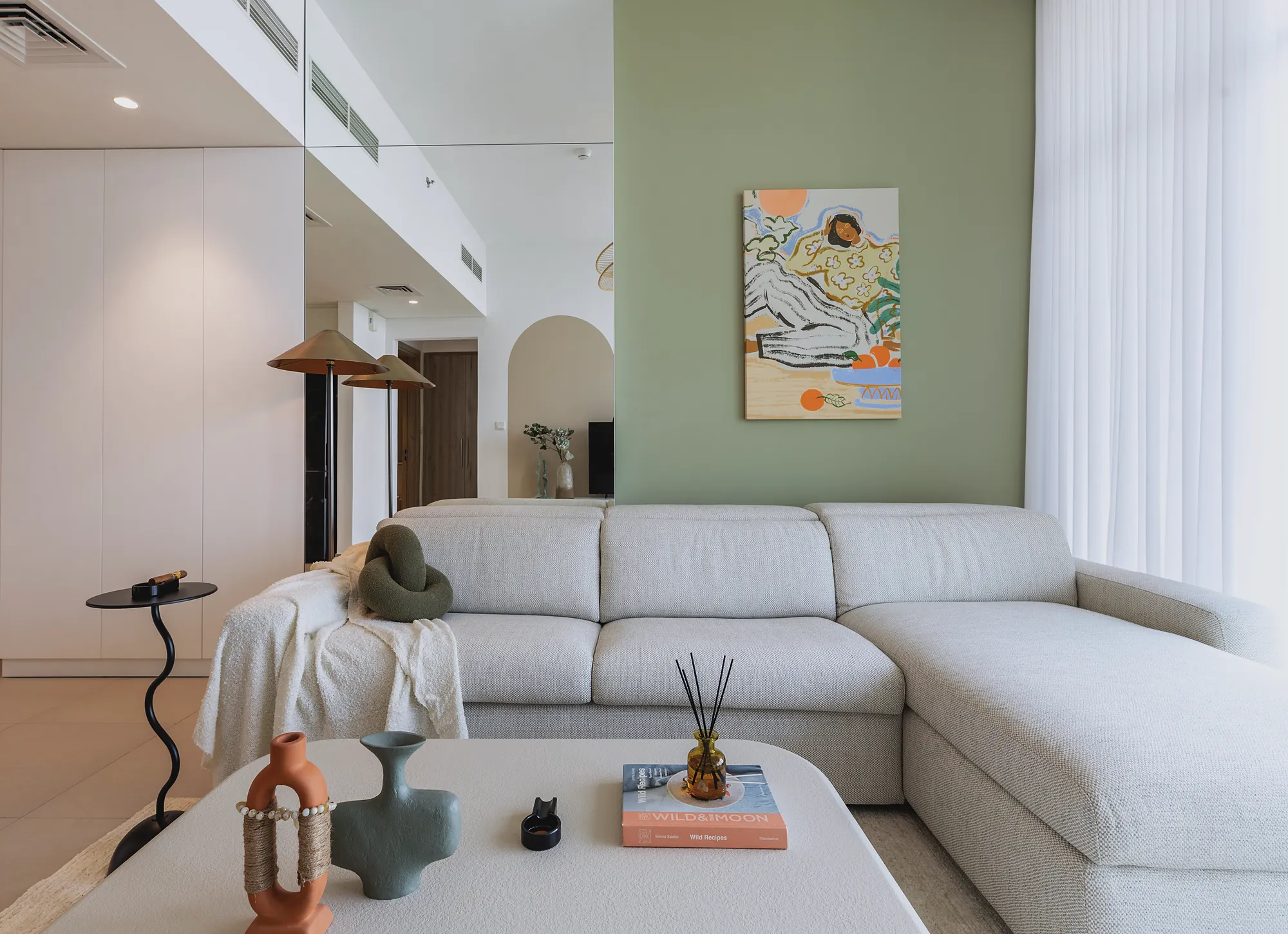 Prive 702 lounge detail with linen corner sofa, sage wall and brass floor lamps